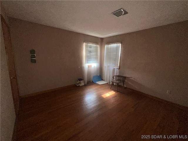 unfurnished room featuring hardwood / wood-style flooring and a textured ceiling