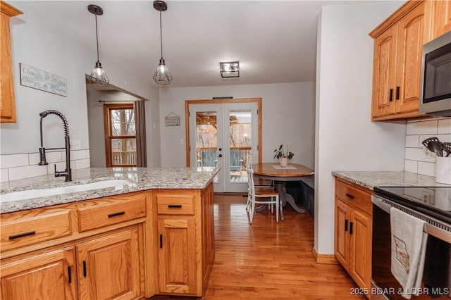 kitchen featuring light stone counters, electric range oven, decorative light fixtures, and french doors