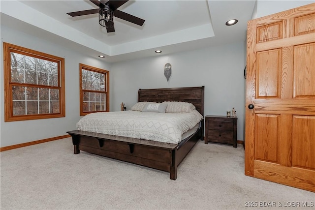 bedroom with ceiling fan, light colored carpet, and a raised ceiling