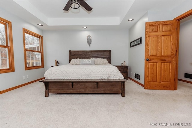 bedroom featuring light colored carpet, ceiling fan, and a tray ceiling