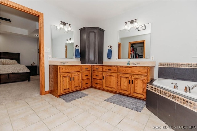 bathroom featuring tile patterned floors, vanity, and tiled bath