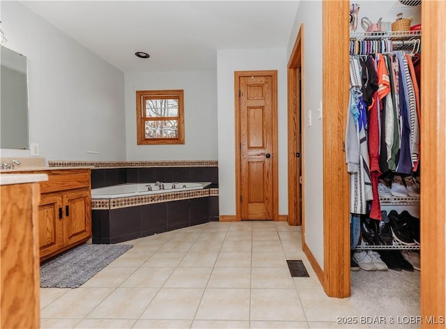 bathroom featuring tile patterned floors, vanity, and tiled tub