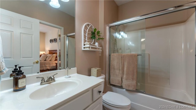 full bathroom with enclosed tub / shower combo, vanity, and toilet