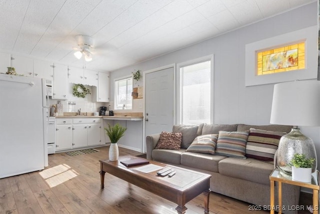 living room with sink, light hardwood / wood-style floors, and ceiling fan