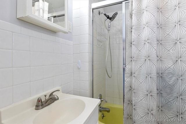 bathroom featuring tile walls, sink, and tiled shower / bath