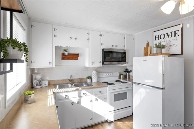 kitchen with a healthy amount of sunlight, sink, white appliances, and white cabinets