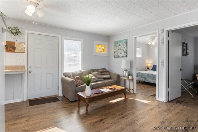 living room featuring hardwood / wood-style floors, plenty of natural light, ornamental molding, and ceiling fan