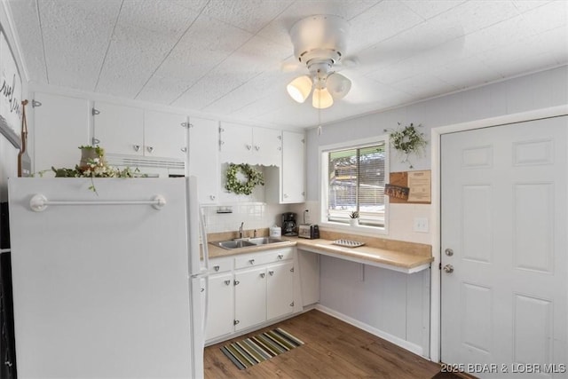 kitchen featuring sink, white cabinetry, wood-type flooring, white refrigerator, and ceiling fan