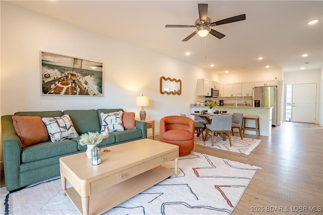 living room featuring sink, light hardwood / wood-style floors, and ceiling fan