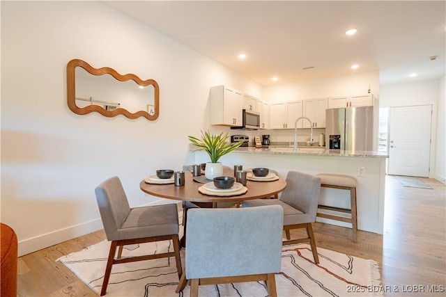 dining space with sink and light hardwood / wood-style flooring