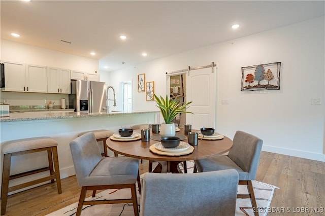 dining room featuring sink, a barn door, and light wood-type flooring