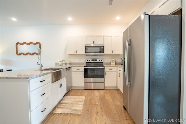 kitchen featuring white cabinetry, light hardwood / wood-style flooring, kitchen peninsula, stainless steel appliances, and light stone countertops