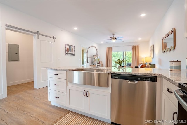 kitchen featuring dishwasher, electric panel, light stone counters, white cabinets, and a barn door