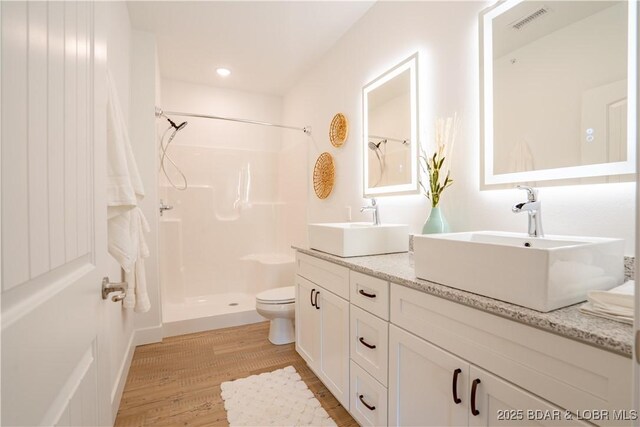 bathroom featuring walk in shower, vanity, toilet, and hardwood / wood-style floors