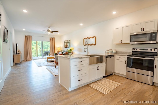 kitchen with white cabinetry, stainless steel appliances, kitchen peninsula, and light wood-type flooring