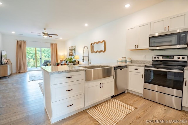 kitchen with appliances with stainless steel finishes, sink, white cabinets, and kitchen peninsula