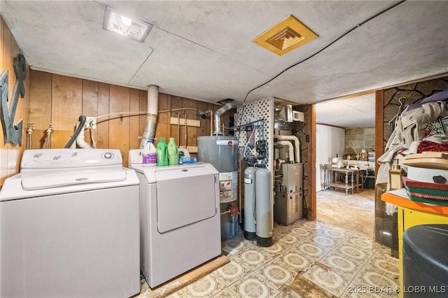 laundry area featuring gas water heater, independent washer and dryer, and wood walls