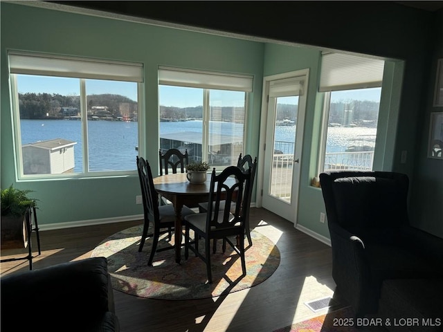 dining area with dark hardwood / wood-style floors, a healthy amount of sunlight, and a water view