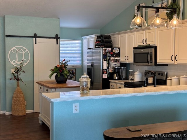 kitchen with pendant lighting, tasteful backsplash, white cabinets, stainless steel appliances, and a barn door