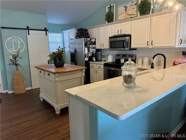 kitchen with decorative light fixtures, white cabinetry, dark hardwood / wood-style flooring, stainless steel appliances, and a barn door