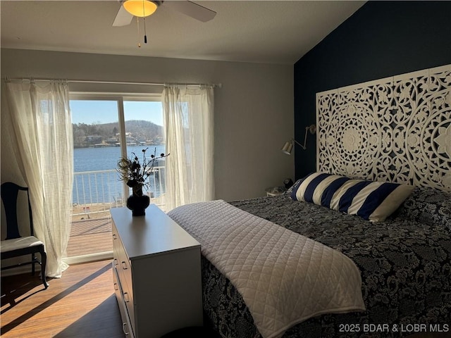 bedroom featuring wood-type flooring, a water view, and ceiling fan