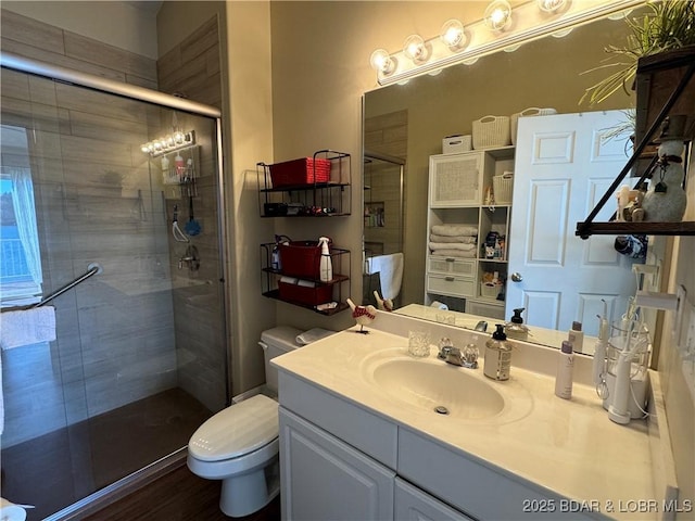 bathroom featuring toilet, vanity, and a shower with shower door