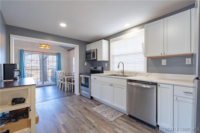 kitchen featuring stainless steel appliances, white cabinetry, sink, and light wood-type flooring