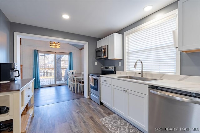 kitchen featuring white cabinetry, sink, light hardwood / wood-style floors, and appliances with stainless steel finishes