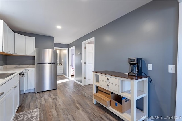 kitchen with stainless steel appliances, white cabinetry, sink, and light wood-type flooring