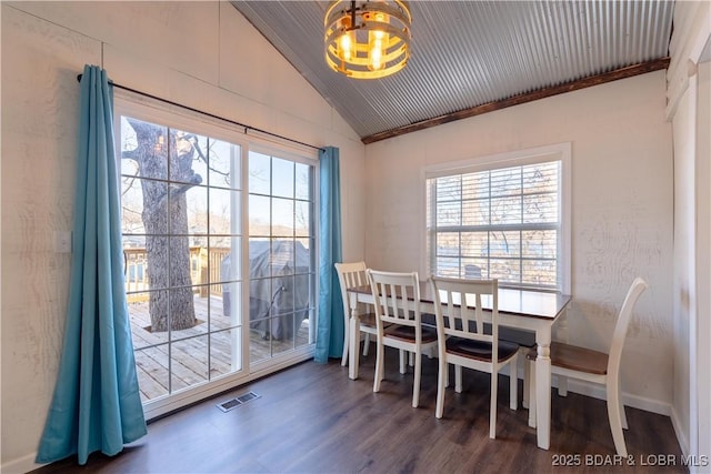 dining room featuring vaulted ceiling, a healthy amount of sunlight, a notable chandelier, and dark hardwood / wood-style flooring