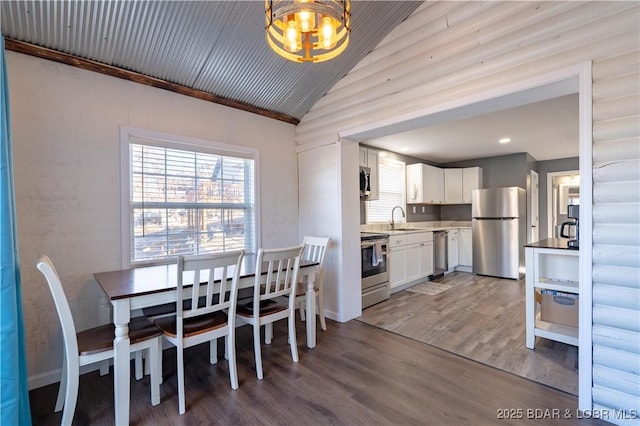 dining space with sink, vaulted ceiling, and hardwood / wood-style floors