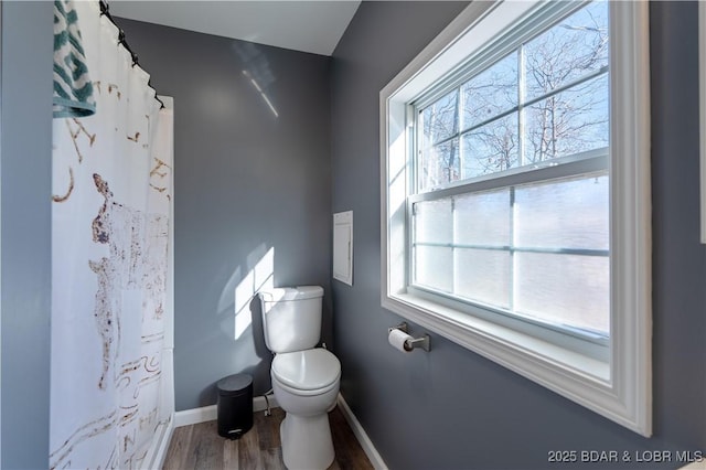 bathroom featuring curtained shower, wood-type flooring, and toilet