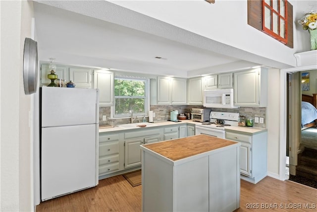 kitchen featuring sink, backsplash, white appliances, and light wood-type flooring