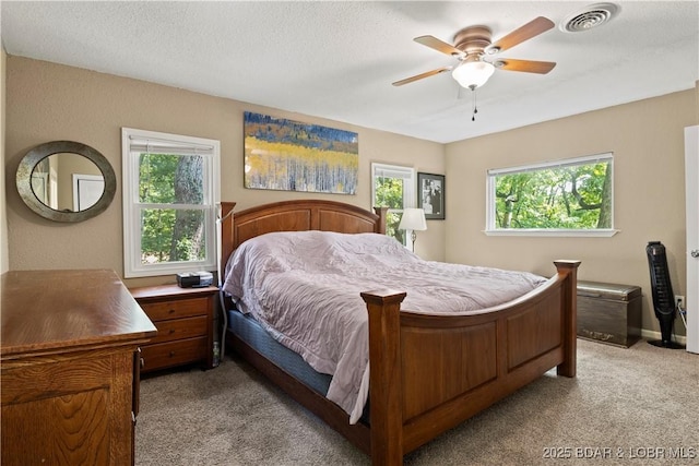 carpeted bedroom featuring ceiling fan and a textured ceiling