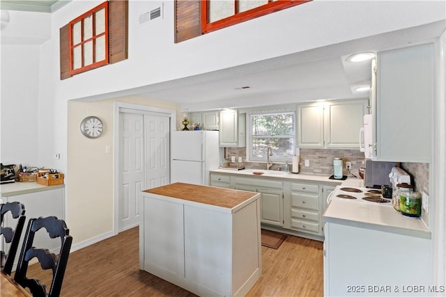 kitchen featuring light hardwood / wood-style floors, a center island, sink, and white fridge