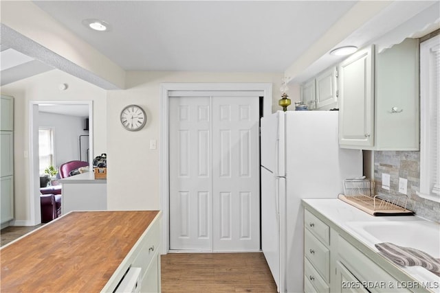 kitchen featuring white cabinetry, backsplash, hardwood / wood-style floors, and white refrigerator