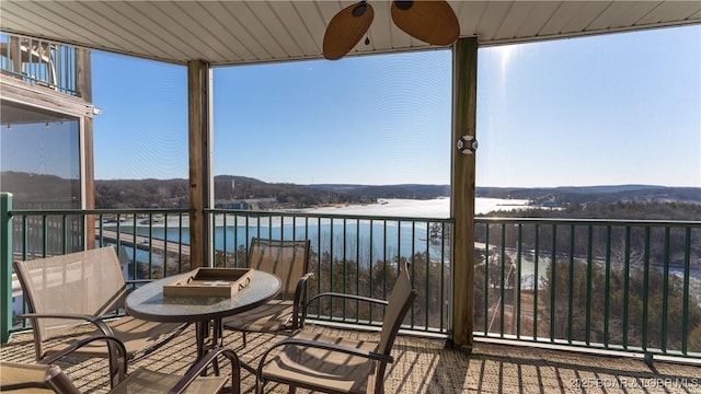 sunroom / solarium featuring a water view and ceiling fan