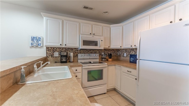 kitchen featuring white cabinetry, sink, white appliances, and light tile patterned floors