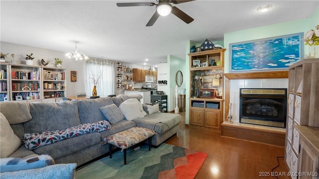 living room with ceiling fan with notable chandelier, a fireplace, and light wood-type flooring