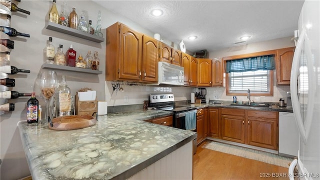 kitchen with sink, white appliances, light hardwood / wood-style floors, decorative backsplash, and kitchen peninsula