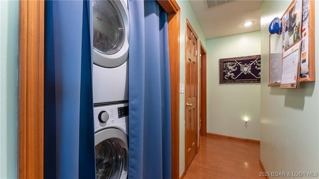 laundry area featuring stacked washer and dryer and light wood-type flooring