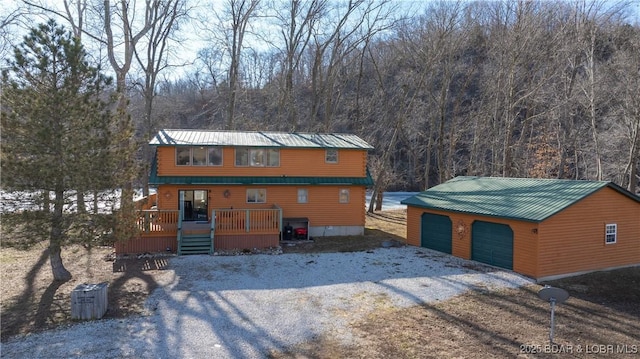 rustic home featuring a garage, metal roof, a deck, and an outdoor structure