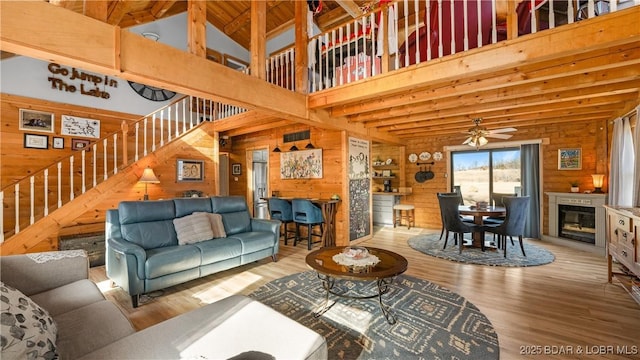 living room featuring ceiling fan, wooden walls, hardwood / wood-style floors, and a high ceiling