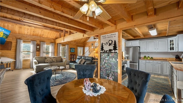 dining area featuring wooden walls, sink, ceiling fan, wooden ceiling, and light wood-type flooring