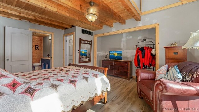 bedroom with beam ceiling, light hardwood / wood-style floors, and wooden ceiling