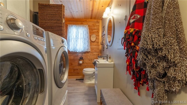 laundry area featuring dark wood-type flooring, wooden walls, wooden ceiling, and washing machine and dryer