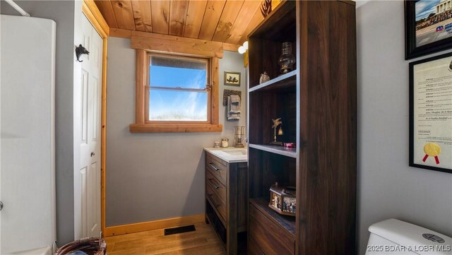 bathroom with vanity, hardwood / wood-style flooring, wooden ceiling, and toilet