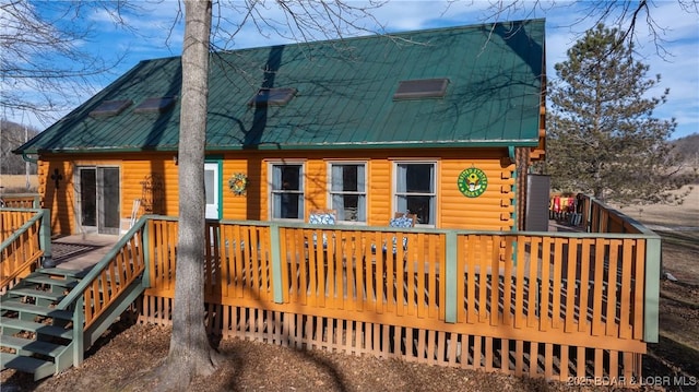 rear view of property featuring metal roof, log exterior, and a wooden deck