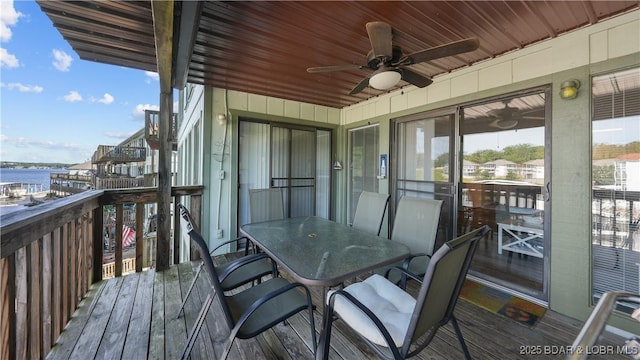 wooden terrace with a water view and ceiling fan