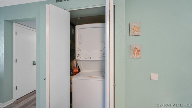 laundry room with wood-type flooring and stacked washer and clothes dryer